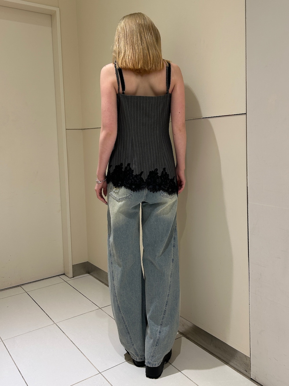 ブルー系のデニムパンツ、ブラック系のブーツ、グレー系のキャミソールを着用したレディースの春コーディネートの3枚目の写真