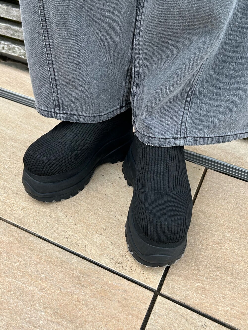 ブラック系のデニムパンツ、ブルー系のTシャツ/カットソー、ブラック系のブーツを着用したレディースの春コーディネートの6枚目の写真