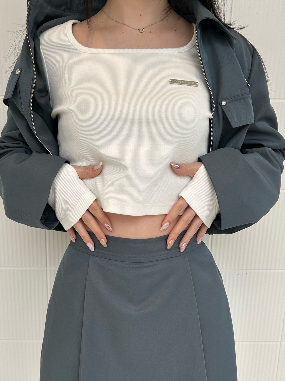 グレー系のスカート、グレー系のブルゾン、ホワイト系のTシャツ/カットソーを着用したレディースの春コーディネートの6枚目の写真