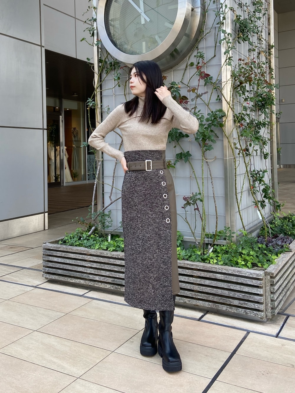 ブルー系のステンカラーコート、ベージュ系のニット/セーター、ブラウン系のスカートを着用したレディースの秋コーディネートの5枚目の写真