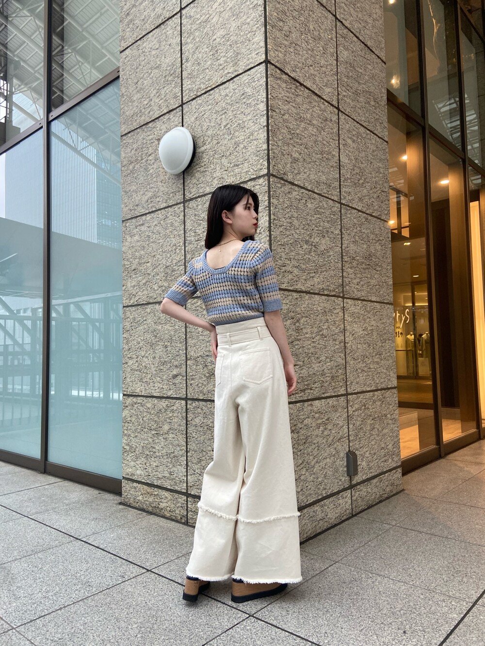 ブルー系のニット/セーター、ホワイト系のデニムパンツ、ブラック系のサンダルを着用したレディースの春コーディネートの3枚目の写真