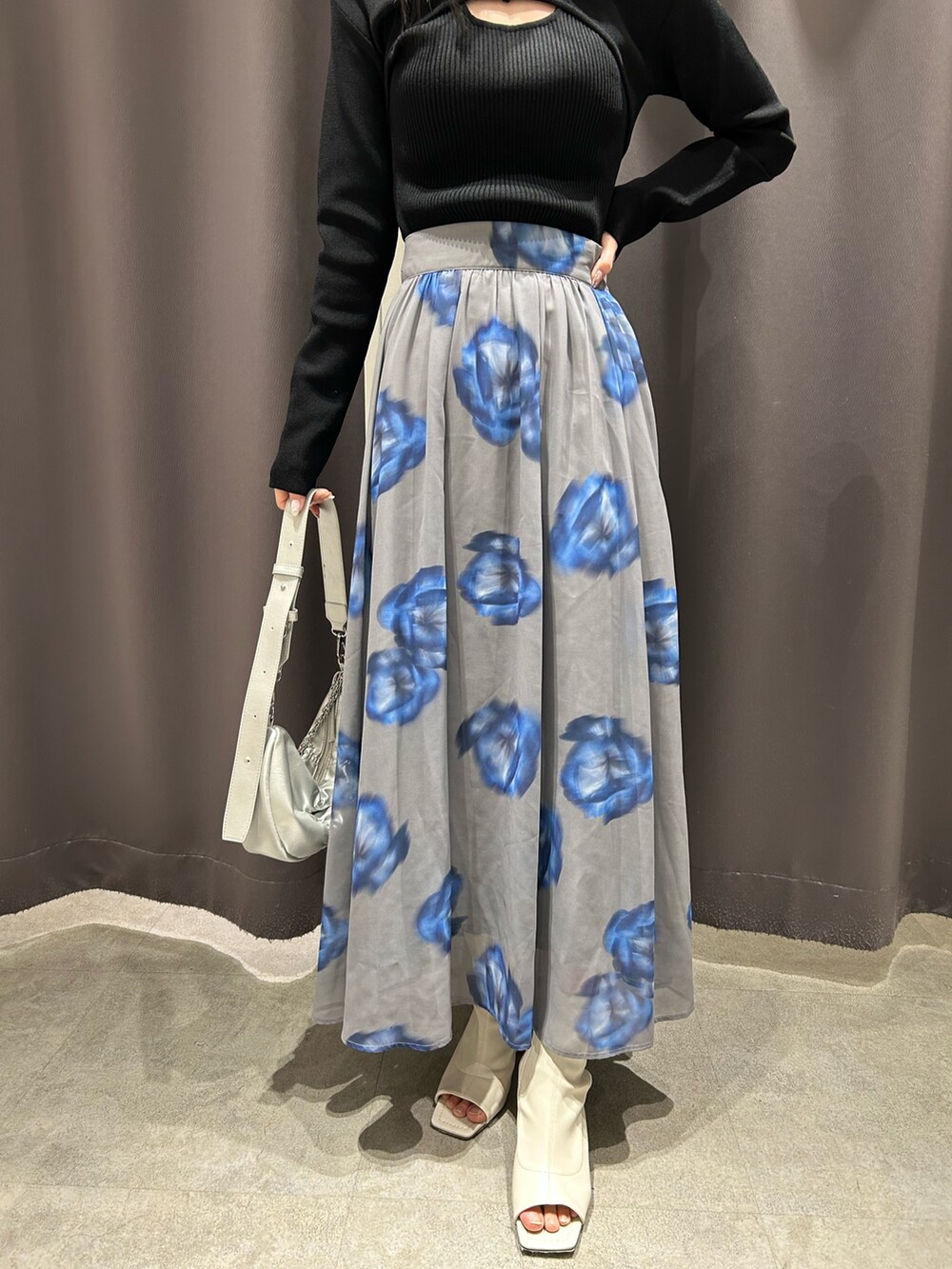 ブラック系のニット/セーター、グレー系のスカート、ホワイト系のブーツを着用したレディースの春コーディネートの5枚目の写真