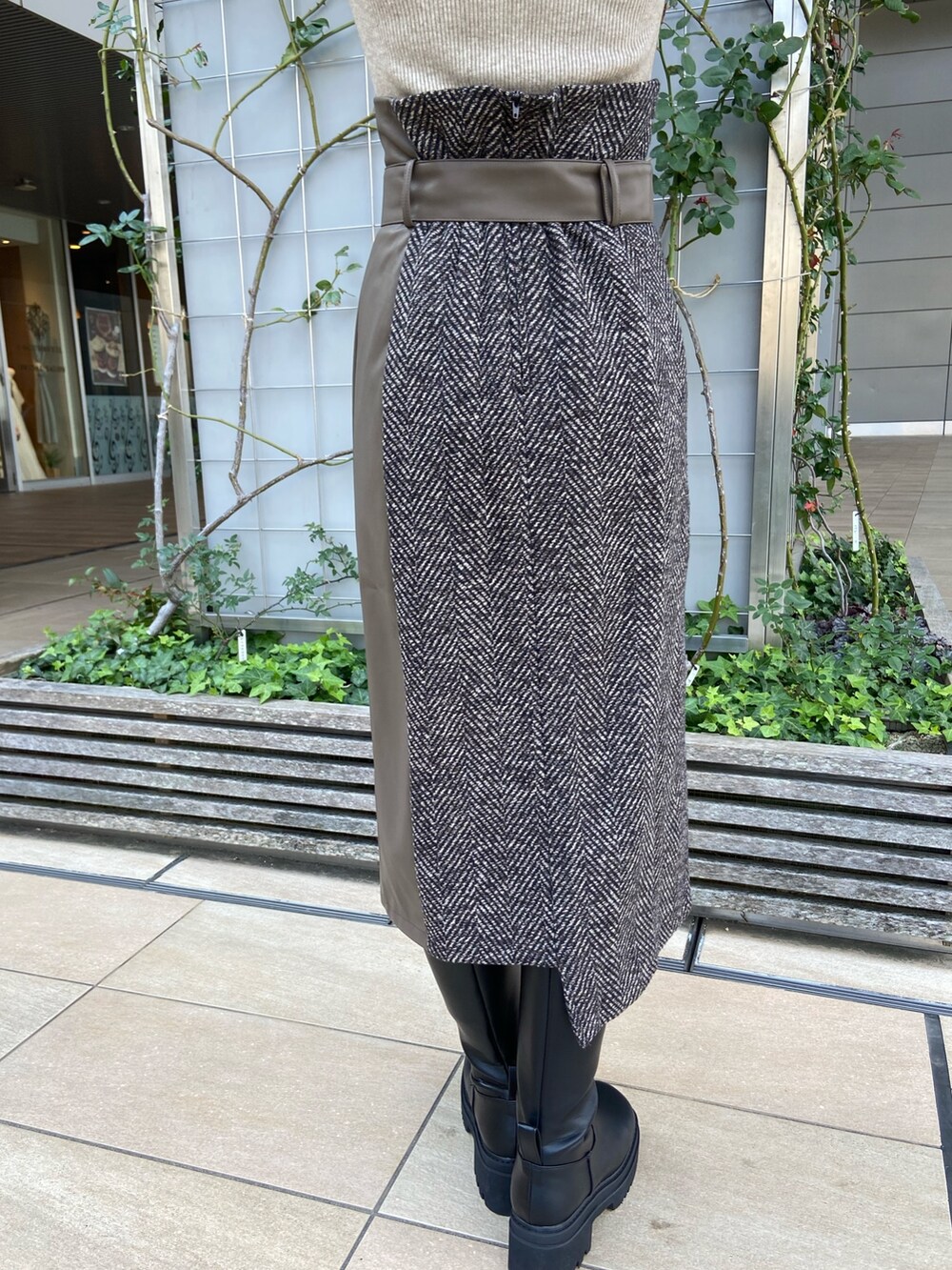 ブルー系のステンカラーコート、ベージュ系のニット/セーター、ブラウン系のスカートを着用したレディースの秋コーディネートの9枚目の写真