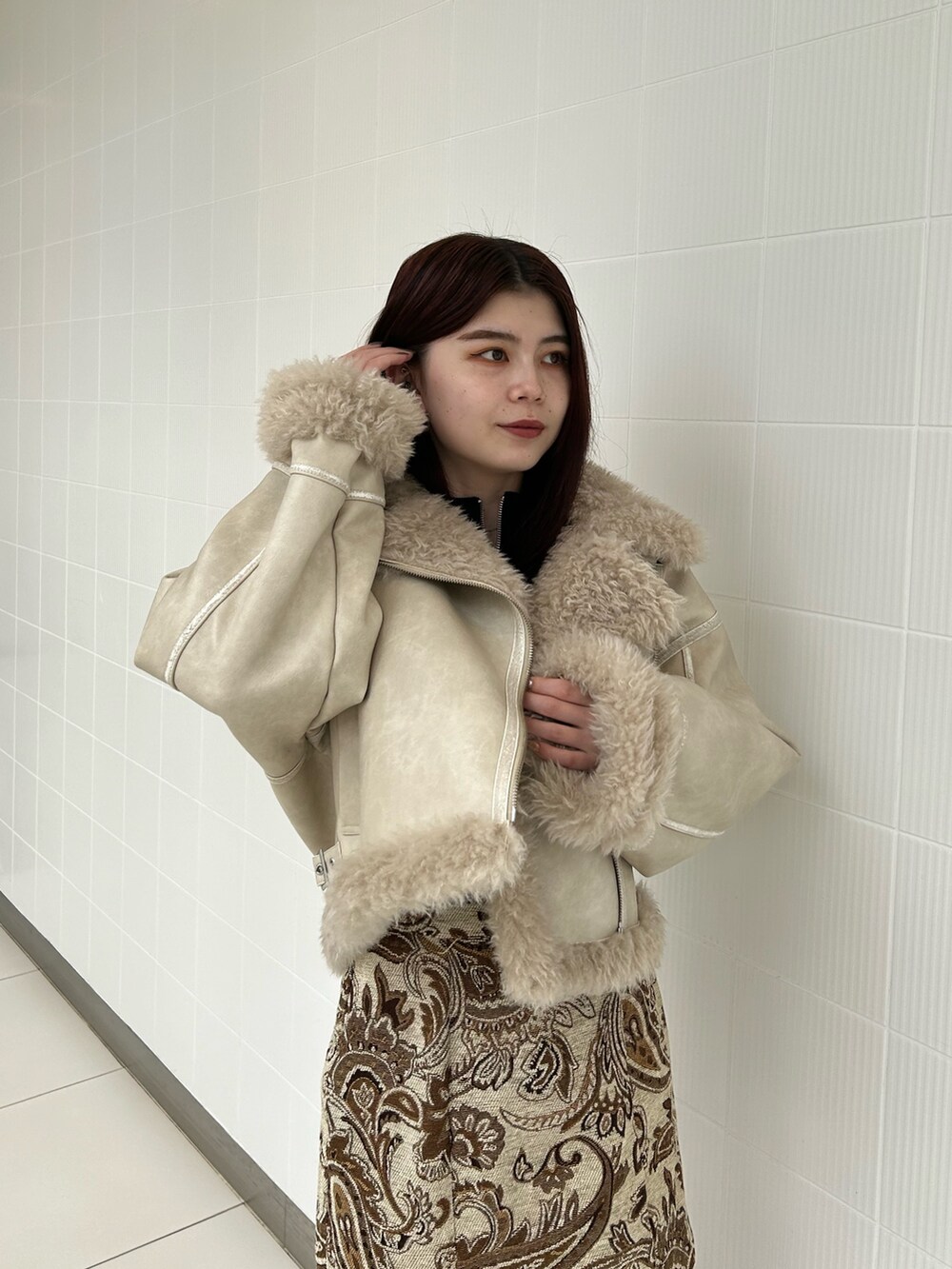 ホワイト系のスカート、ブラック系のニット/セーター、ホワイト系のムートンコートを着用したレディースの秋コーディネートの4枚目の写真