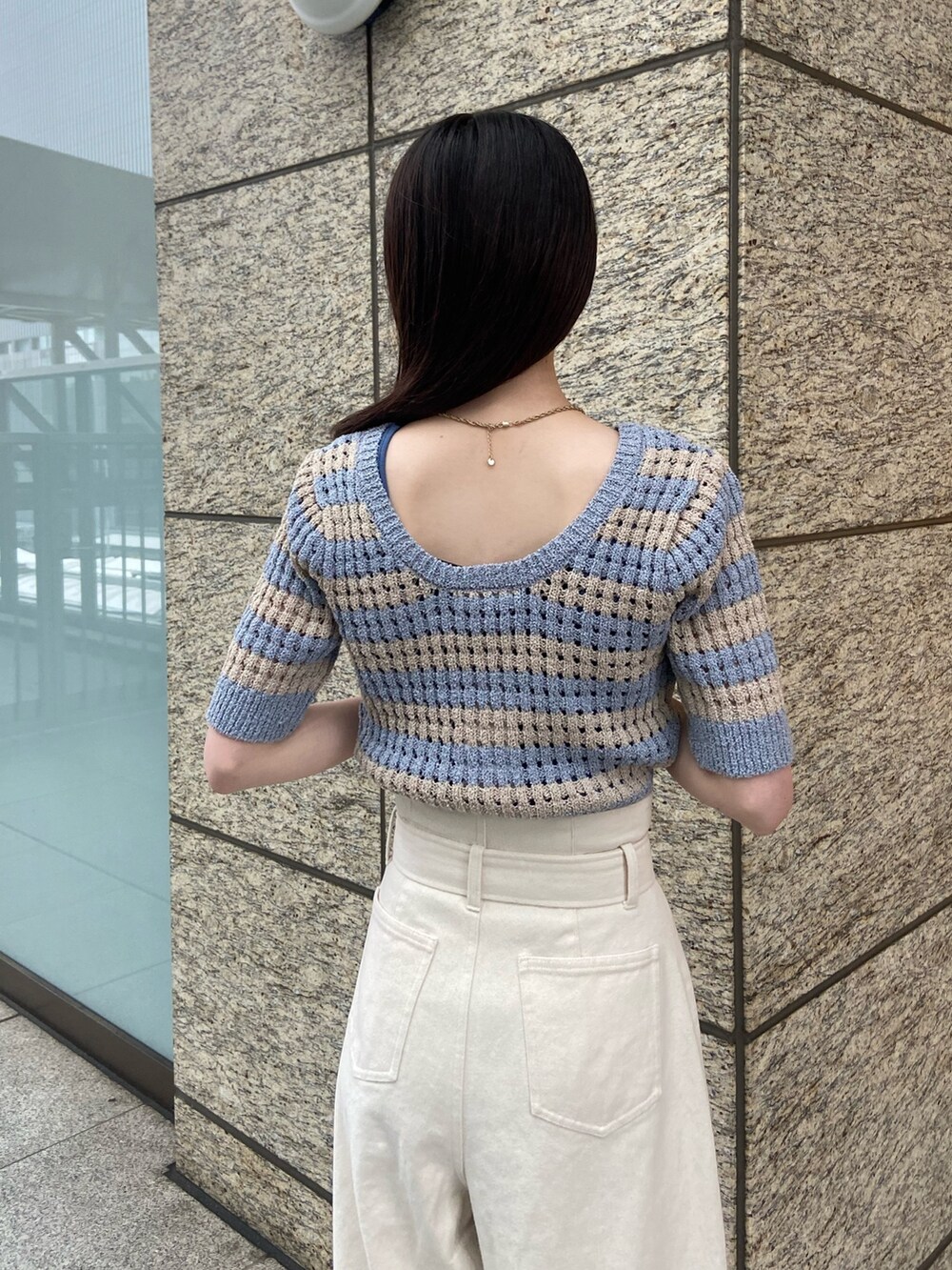 ブルー系のニット/セーター、ホワイト系のデニムパンツ、ブラック系のサンダルを着用したレディースの春コーディネートの5枚目の写真