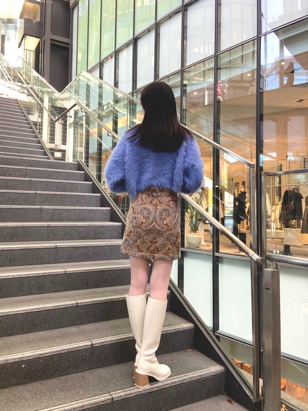 ブルー系のスカート、ブルー系のニット/セーター、ホワイト系のブーツを着用したレディースの秋コーディネートの3枚目の写真