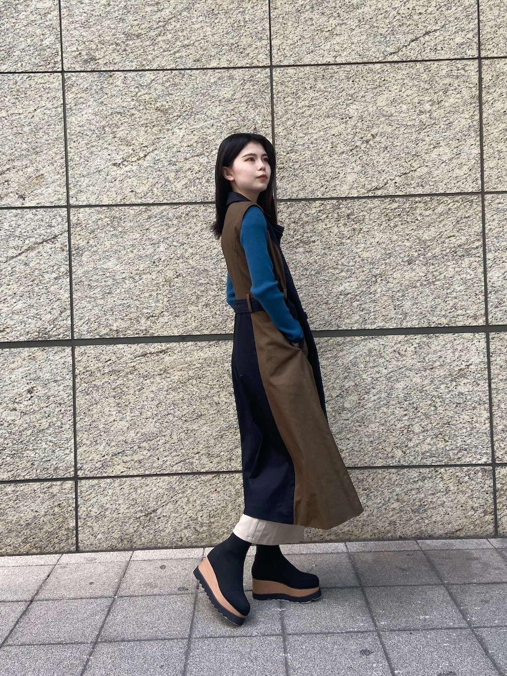 ブルー系のトレンチコート、ホワイト系のスカート、ブラック系のブーツを着用したレディースの秋コーディネートの2枚目の写真