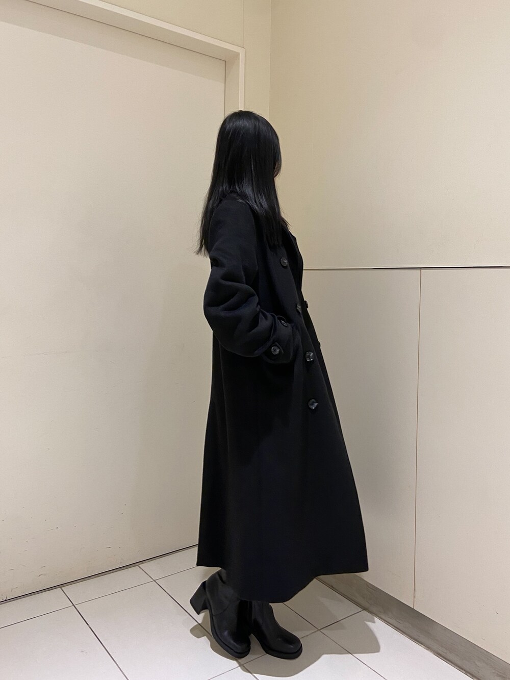 グリーン系のニット/セーター、ブラック系のチェスターコート、ブラック系のスカートを着用したレディースの冬コーディネートの2枚目の写真