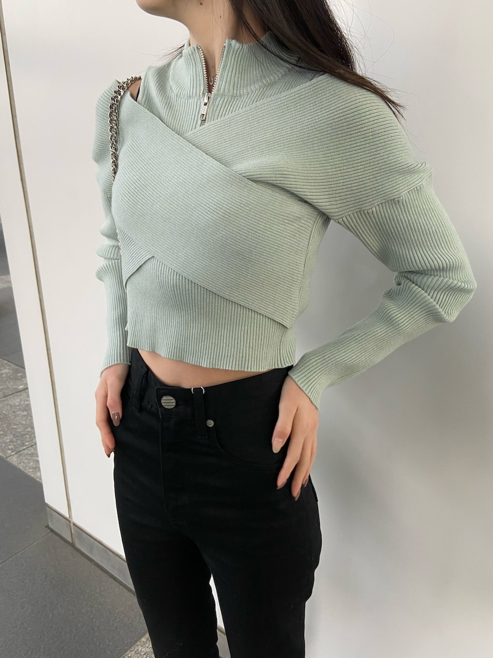 ブラック系のデニムパンツ、ブルー系のニット/セーター、ホワイト系のハンドバッグを着用したレディースの冬コーディネートの6枚目の写真