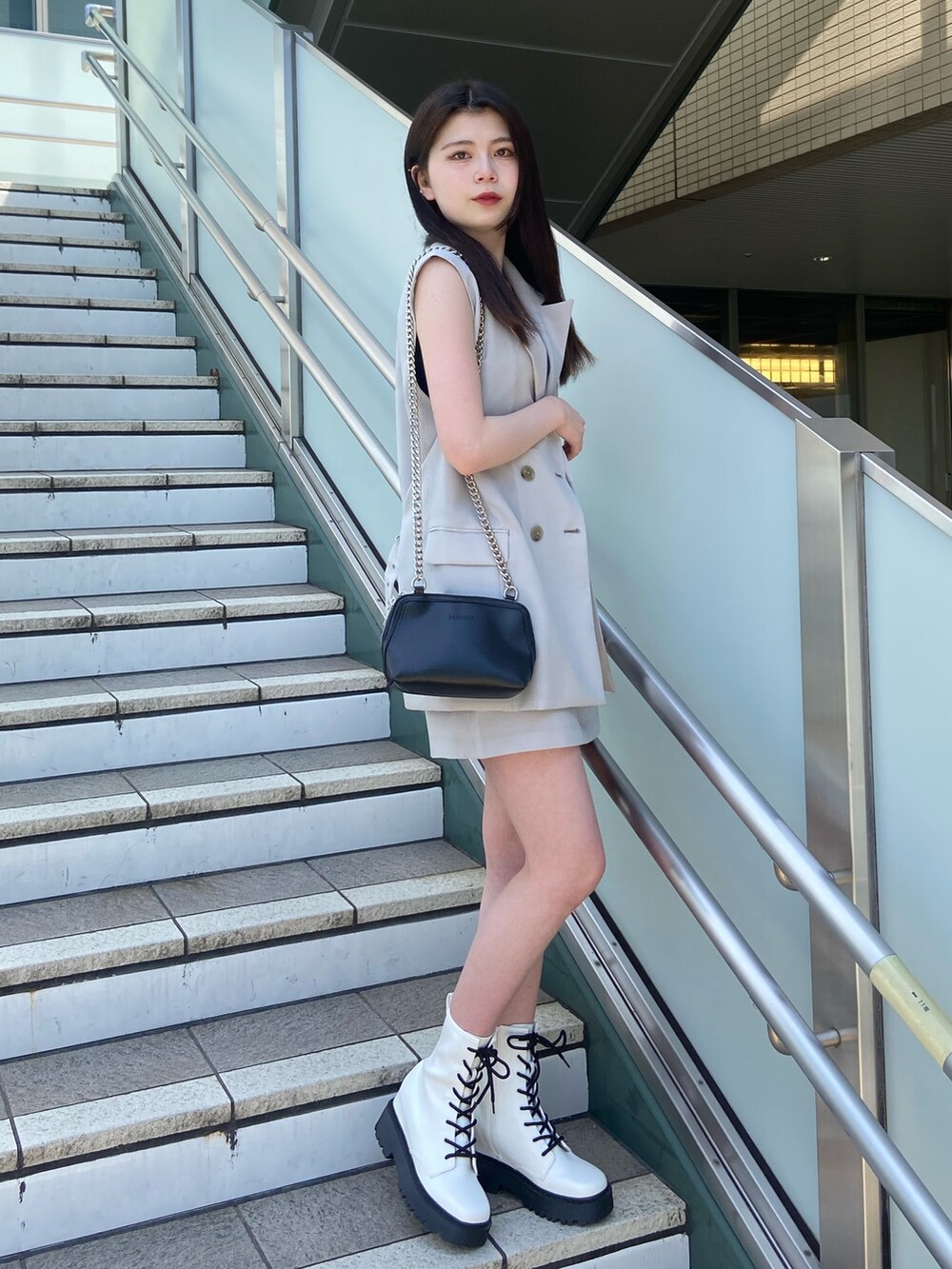 ブルー系のニット/セーター、グレー系のベスト、グレー系のスカートを着用したレディースの春コーディネートの2枚目の写真