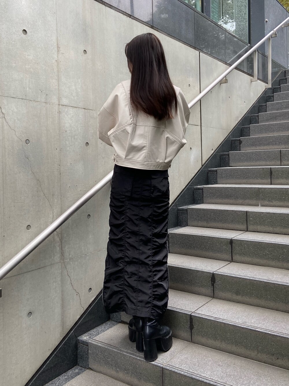 ブラック系のスカート、ブルー系のニット/セーター、ホワイト系のブルゾンを着用したレディースの春コーディネートの3枚目の写真