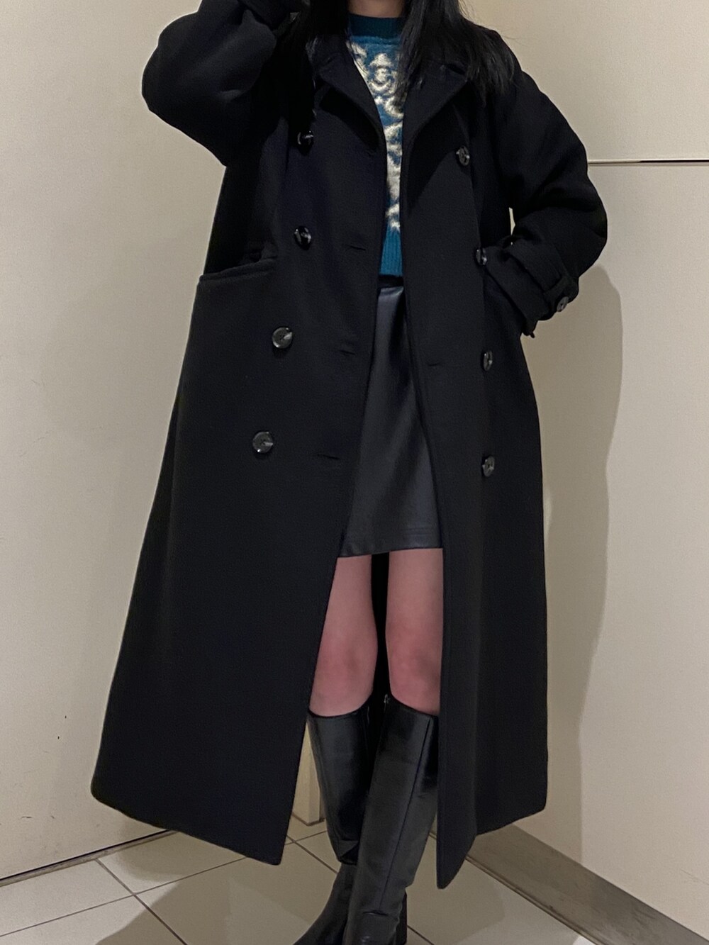 グリーン系のニット/セーター、ブラック系のチェスターコート、ブラック系のスカートを着用したレディースの冬コーディネートの4枚目の写真