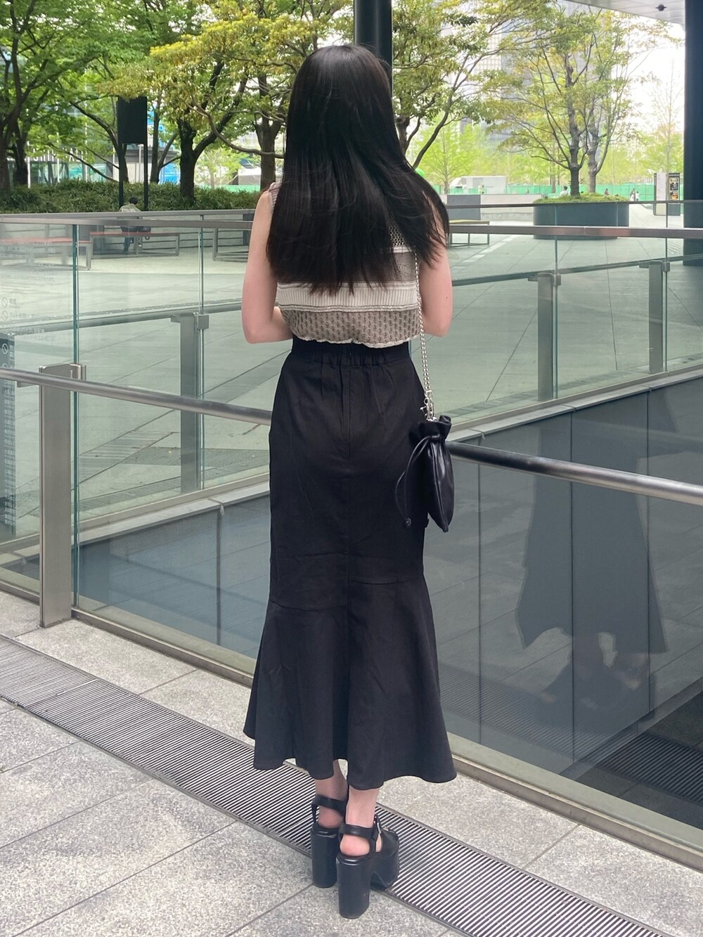 グレー系のニット/セーター、ブラック系のスカート、ブラック系のサンダルを着用したレディースの春コーディネートの3枚目の写真