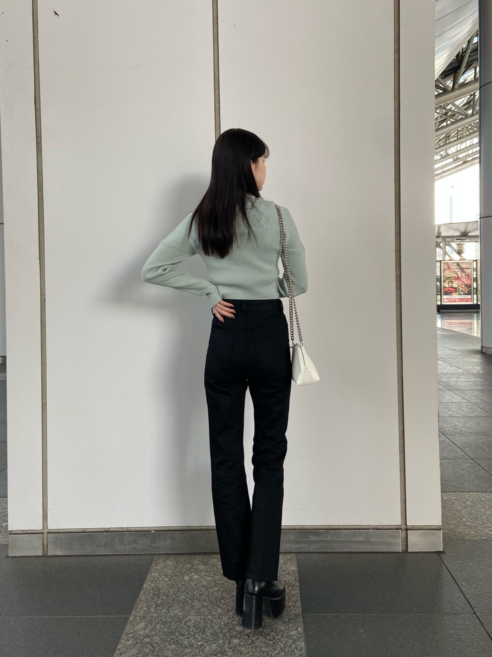 ブラック系のデニムパンツ、ブルー系のニット/セーター、ホワイト系のハンドバッグを着用したレディースの冬コーディネートの3枚目の写真