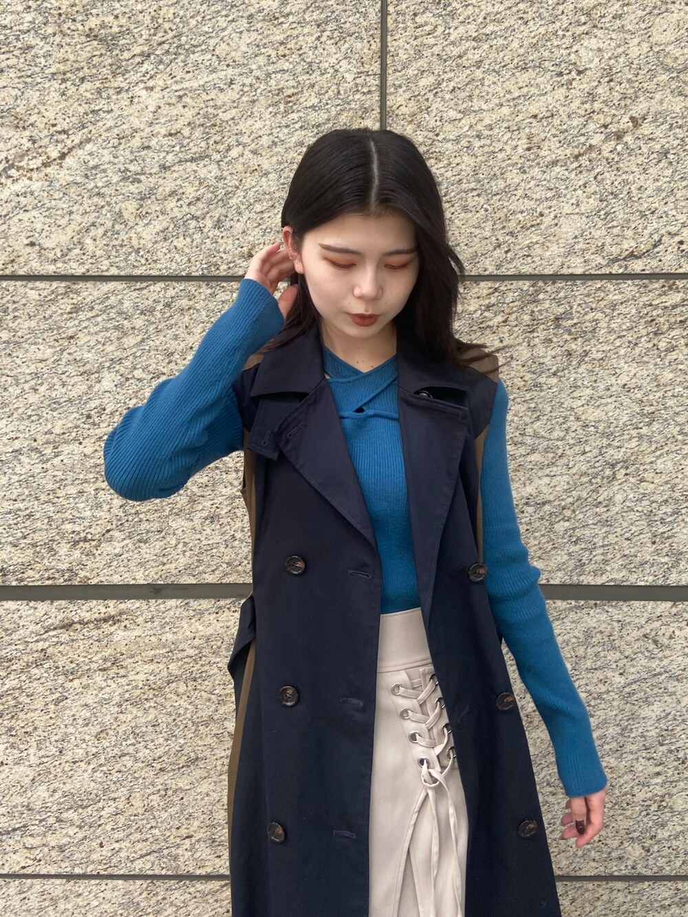 ブルー系のトレンチコート、ホワイト系のスカート、ブラック系のブーツを着用したレディースの秋コーディネートの4枚目の写真