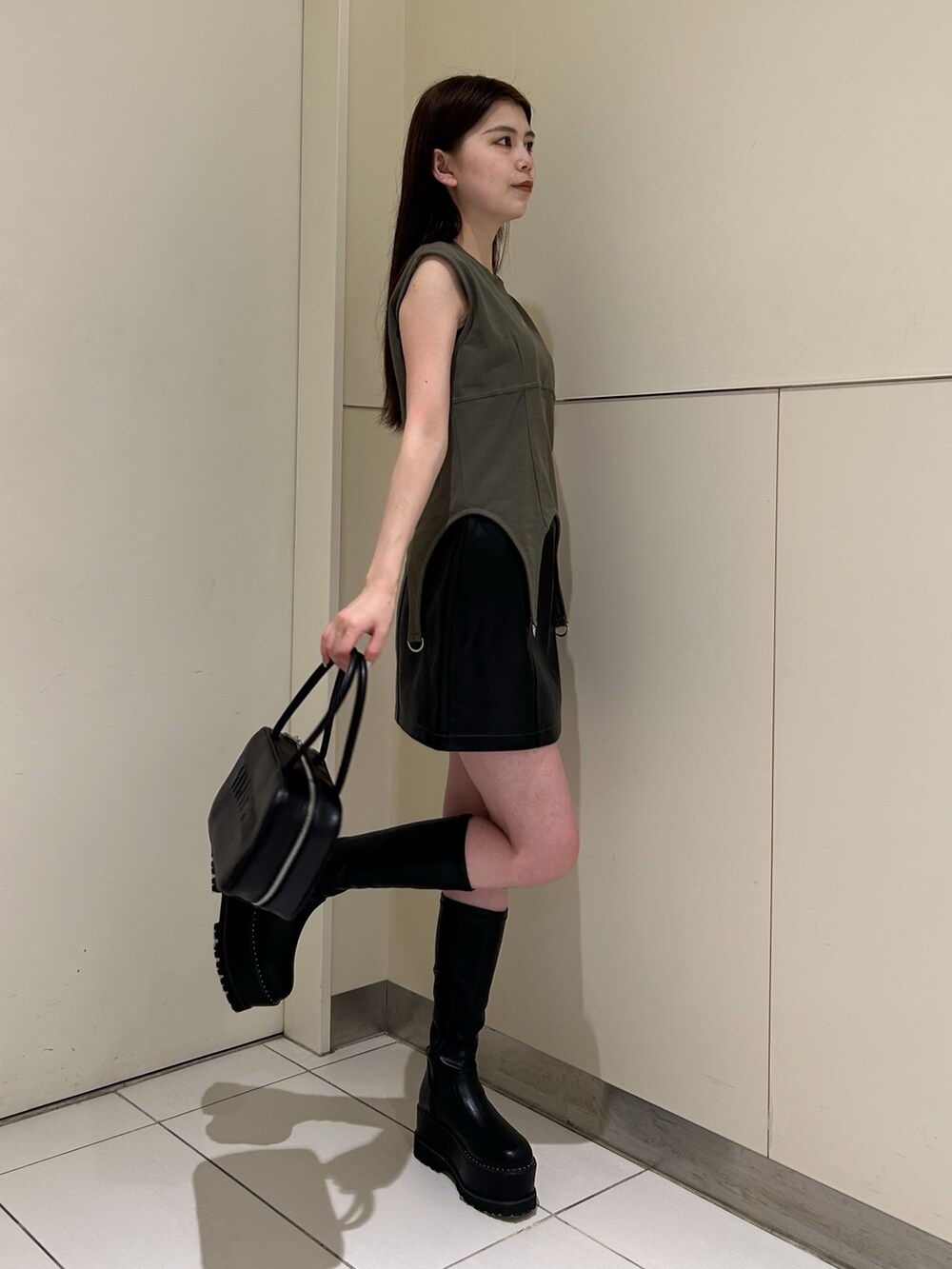 グリーン系のTシャツ/カットソー、ブラック系のスカート、ブラック系のブーツを着用したレディースの秋コーディネートの2枚目の写真