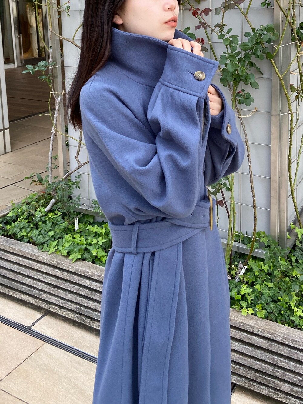 ブルー系のステンカラーコート、ベージュ系のニット/セーター、ブラウン系のスカートを着用したレディースの秋コーディネートの4枚目の写真