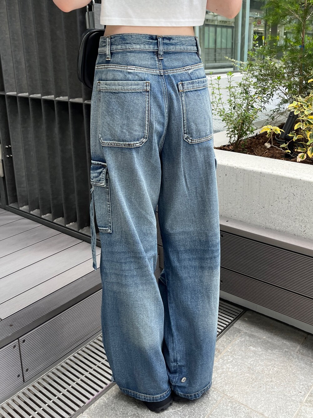 ブルー系のデニムパンツ、ホワイト系のTシャツ/カットソー、ブラック系のボストンバッグを着用したレディースの夏コーディネートの8枚目の写真