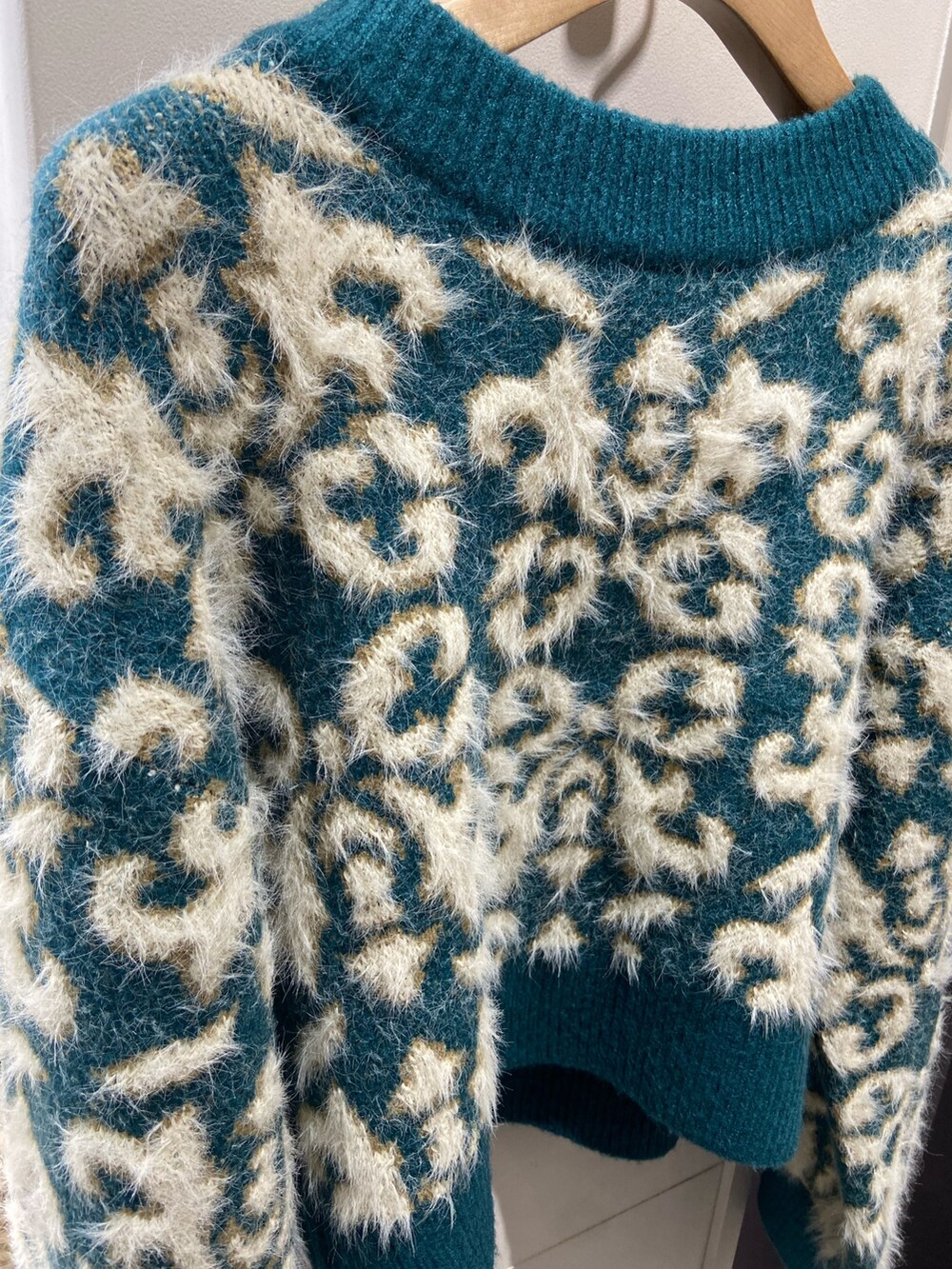 グリーン系のニット/セーター、ブラック系のチェスターコート、ブラック系のスカートを着用したレディースの冬コーディネートの5枚目の写真