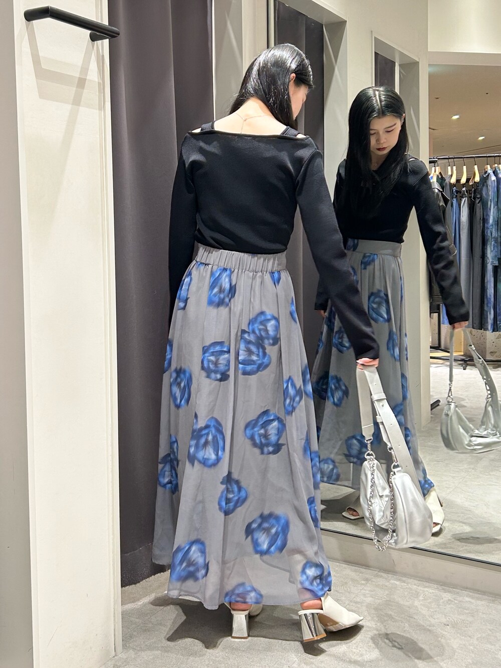 ブラック系のニット/セーター、グレー系のスカート、ホワイト系のブーツを着用したレディースの春コーディネートの3枚目の写真