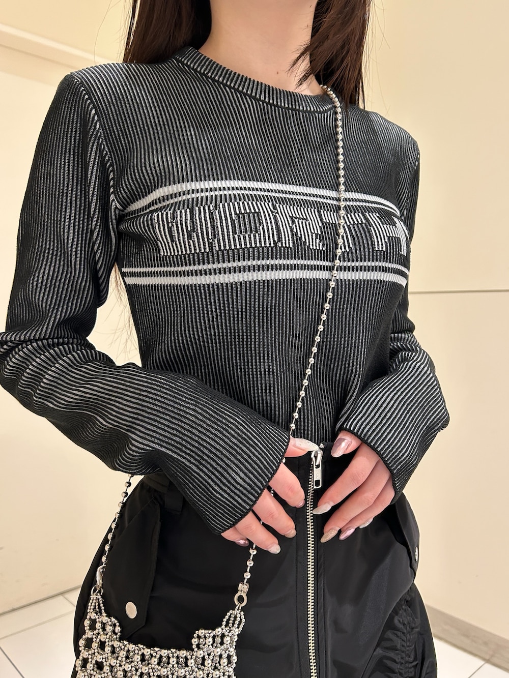 ブラック系のスカート、ブラック系のニット/セーター、ブラック系のブーツを着用したレディースの春コーディネートの4枚目の写真