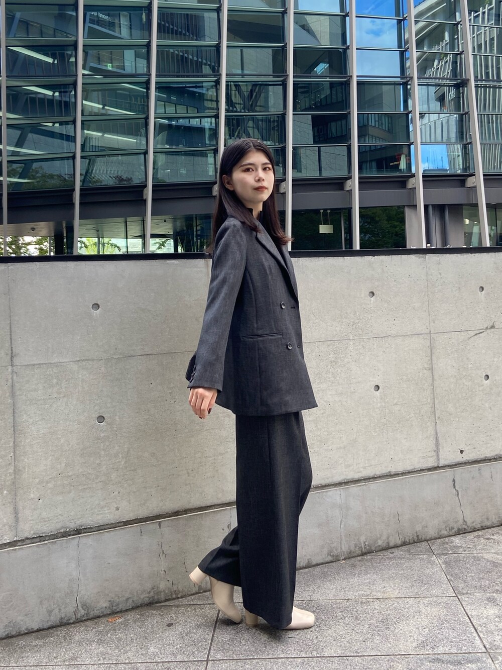 グレー系のテーラードジャケット、ブラック系のニット/セーター、グレー系のスラックスを着用したレディースの秋コーディネートの2枚目の写真