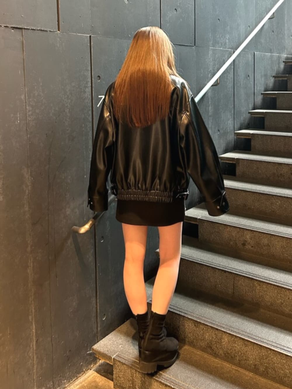 ブラック系のブーツ、ブラック系のブルゾン、ブラック系のスカートを着用したレディースの春コーディネートの3枚目の写真