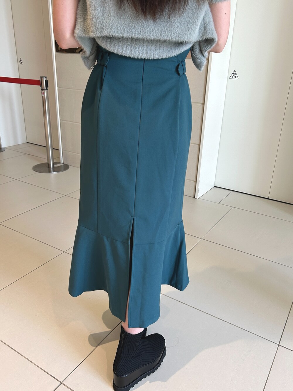 ブルー系のスカート、グレー系のニット/セーター、ブラック系のブーツを着用したレディースの秋コーディネートの7枚目の写真