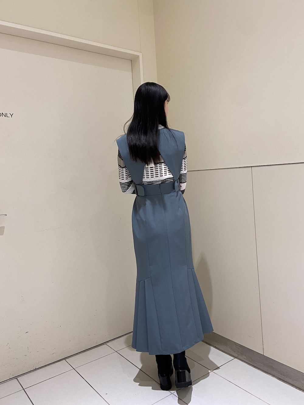 ブルー系のワンピース、ホワイト系のニット/セーター、ブラック系のブーツを着用したレディースの冬コーディネートの3枚目の写真