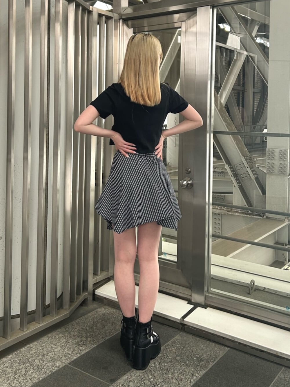 ブラック系のブーツ、ブルー系のスカート、ブラック系のTシャツ/カットソーを着用したレディースの夏コーディネートの2枚目の写真