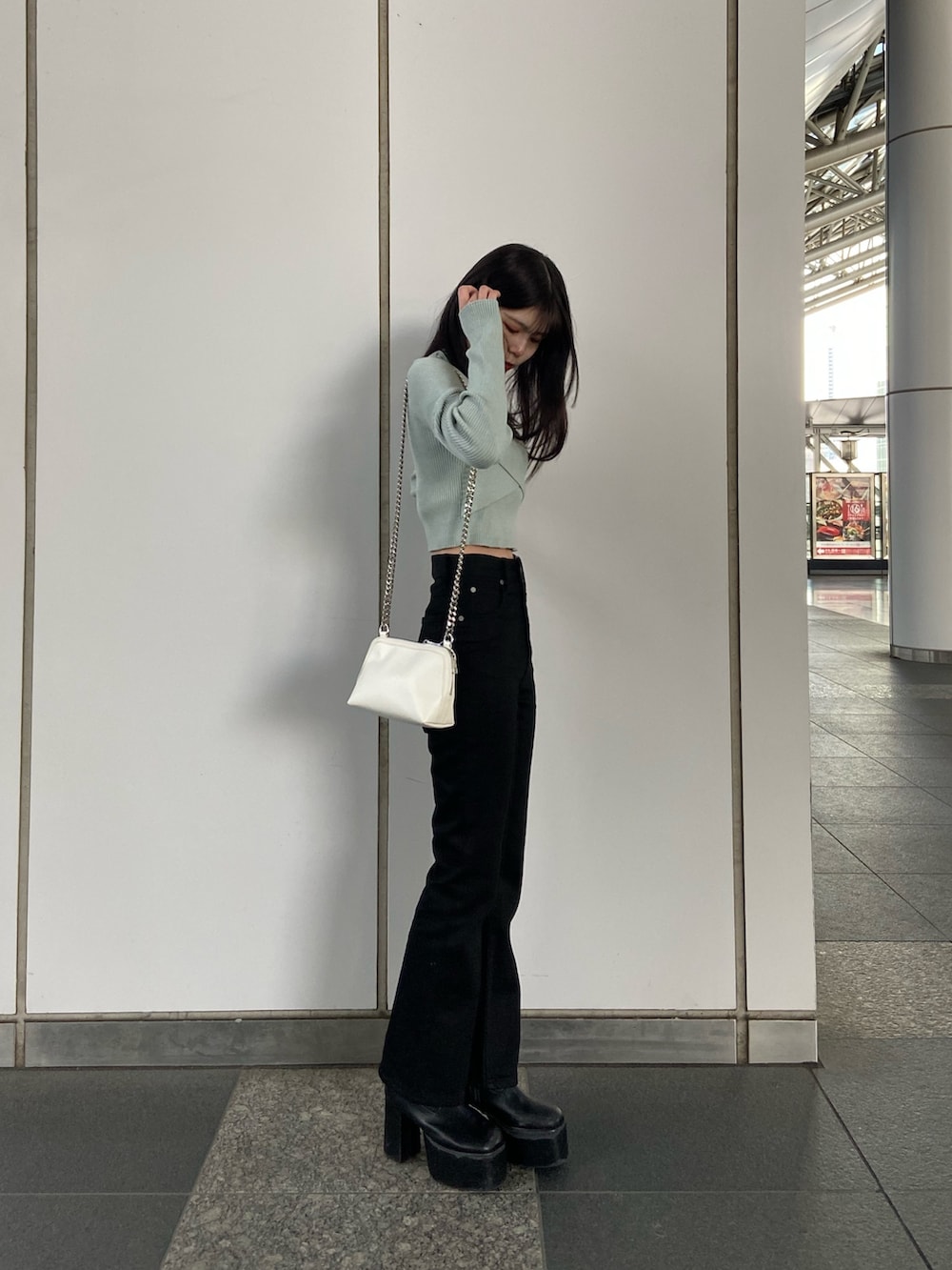 ブラック系のデニムパンツ、ブルー系のニット/セーター、ホワイト系のハンドバッグを着用したレディースの冬コーディネートの2枚目の写真