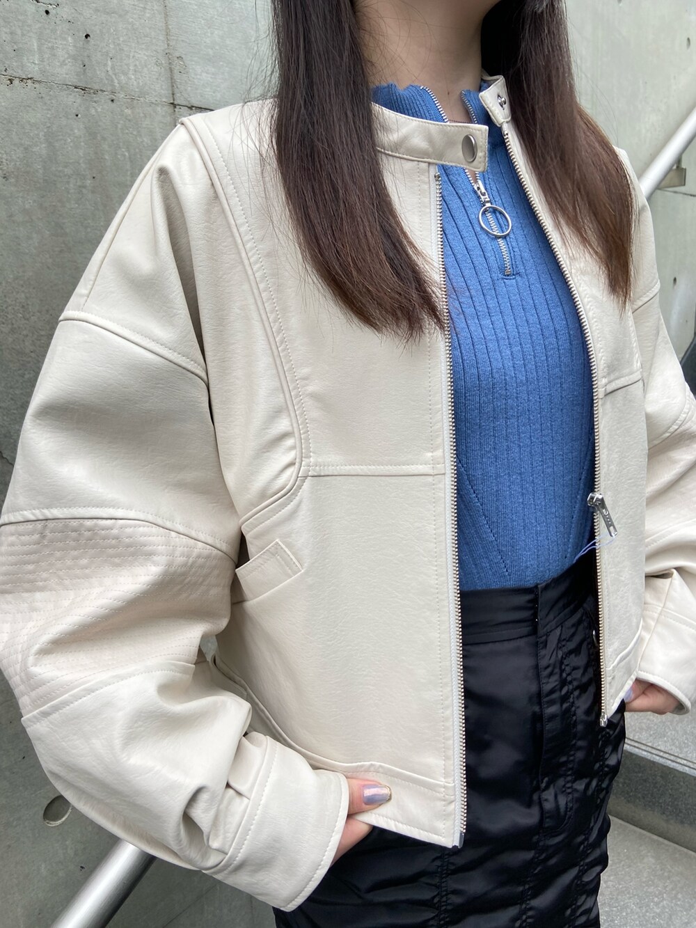 ブラック系のスカート、ブルー系のニット/セーター、ホワイト系のブルゾンを着用したレディースの春コーディネートの4枚目の写真