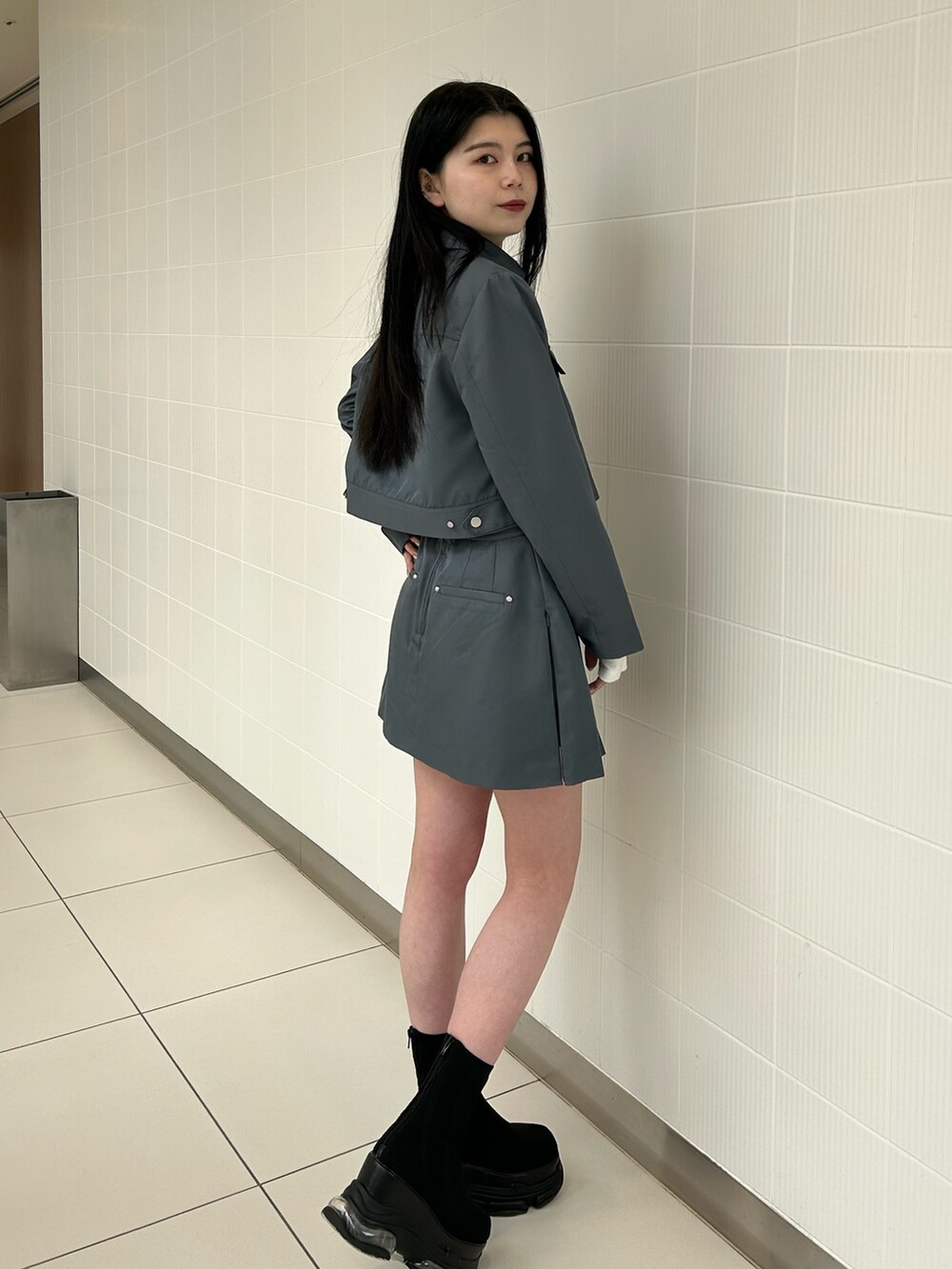 グレー系のスカート、グレー系のブルゾン、ホワイト系のTシャツ/カットソーを着用したレディースの春コーディネートの2枚目の写真