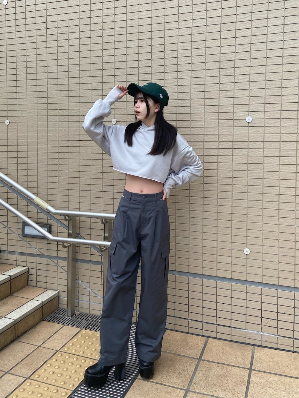 グレー系のカーゴパンツ、グレー系のTシャツ/カットソー、グリーン系のキャップを着用したレディースの冬コーディネートの2枚目の写真