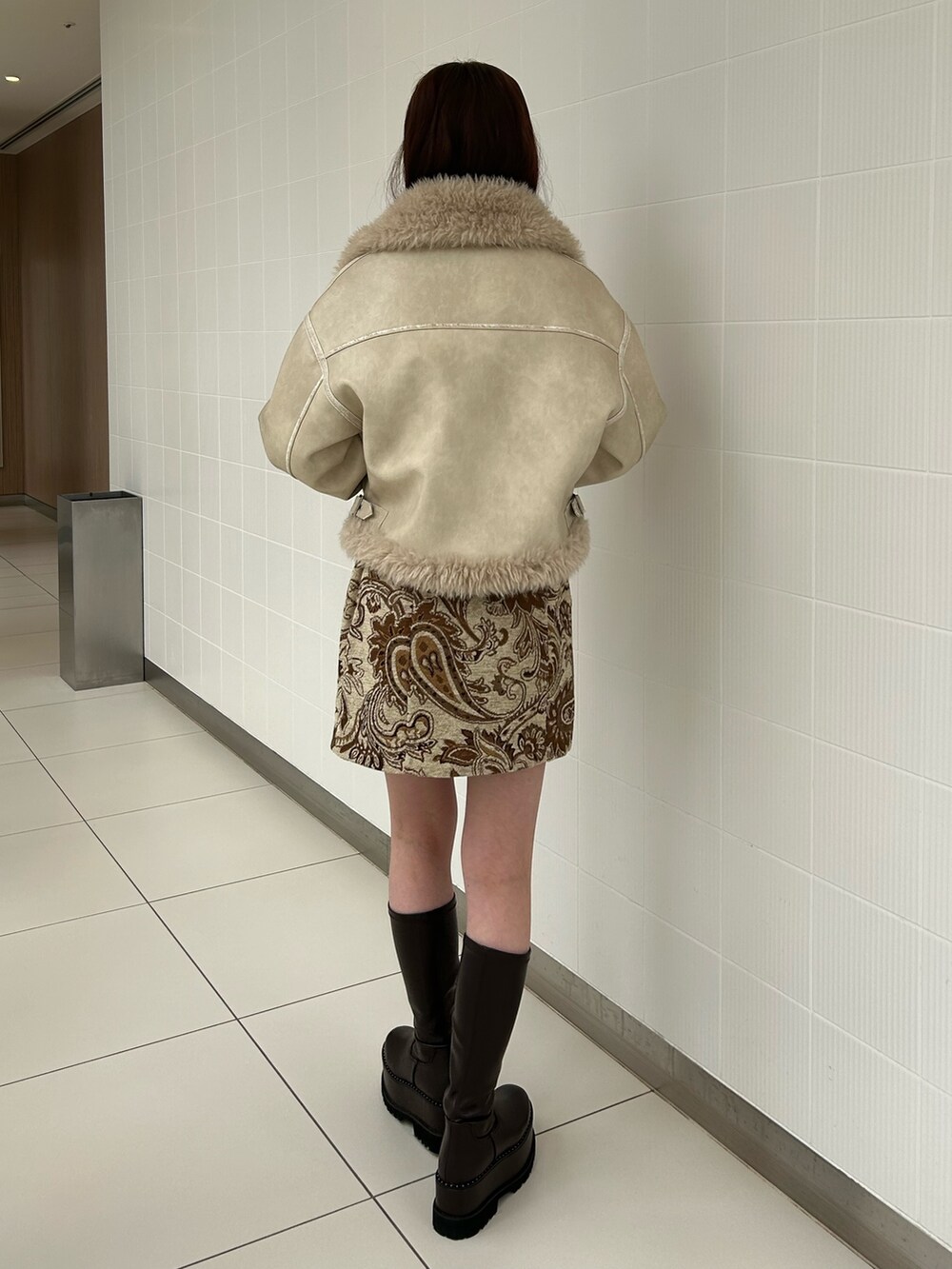 ホワイト系のスカート、ブラック系のニット/セーター、ホワイト系のムートンコートを着用したレディースの秋コーディネートの3枚目の写真