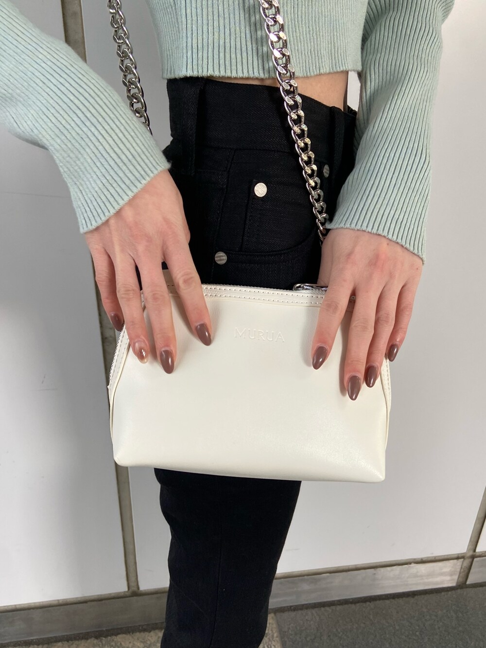 ブラック系のデニムパンツ、ブルー系のニット/セーター、ホワイト系のハンドバッグを着用したレディースの冬コーディネートの7枚目の写真