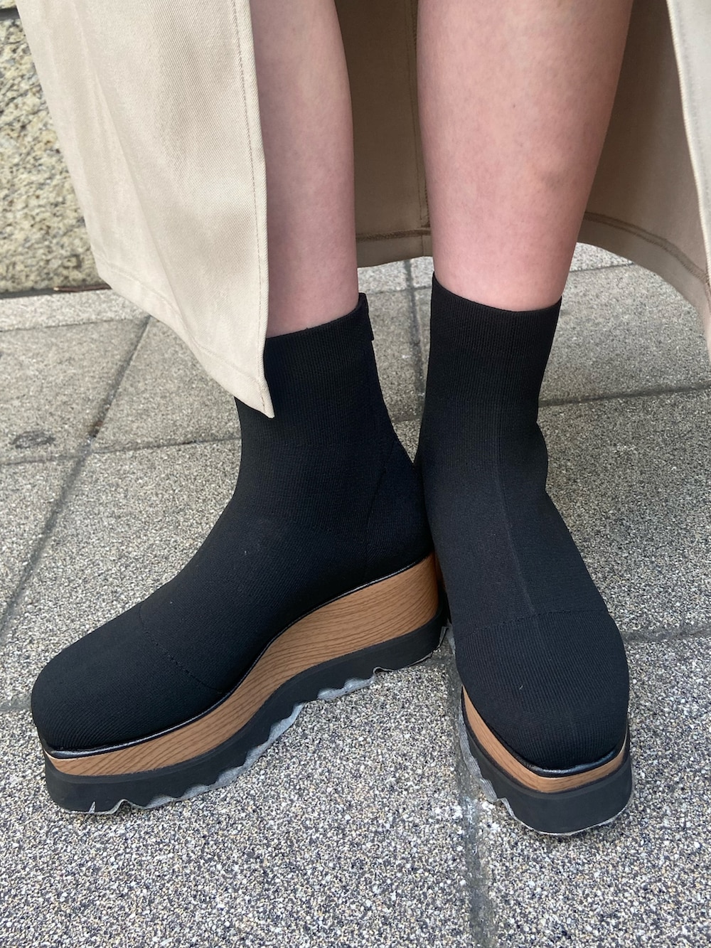 ブルー系のトレンチコート、ホワイト系のスカート、ブラック系のブーツを着用したレディースの秋コーディネートの8枚目の写真