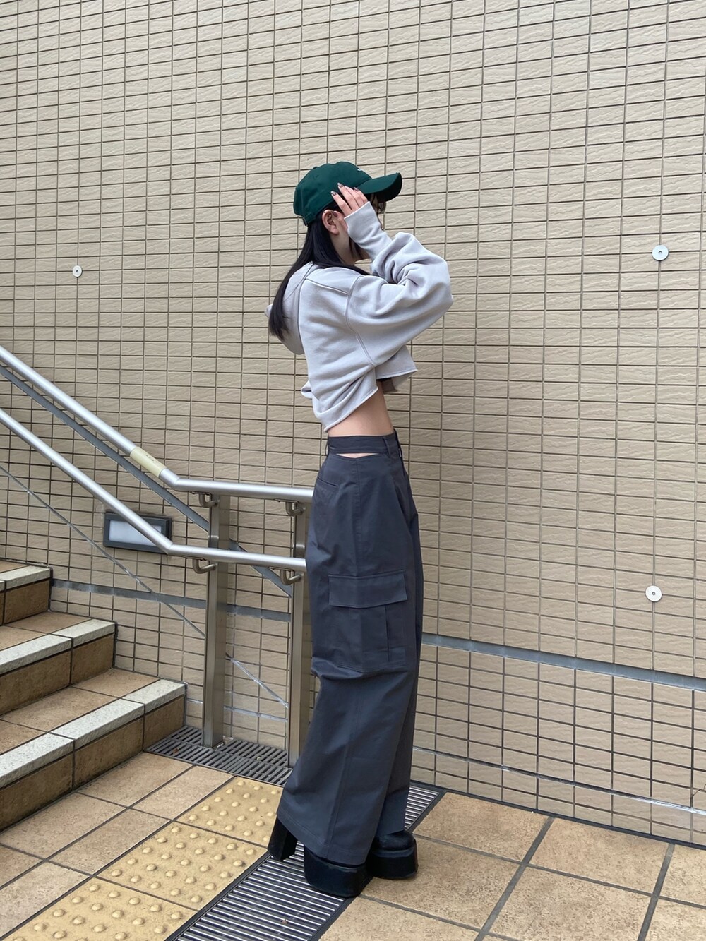 グレー系のカーゴパンツ、グレー系のTシャツ/カットソー、グリーン系のキャップを着用したレディースの冬コーディネートの3枚目の写真