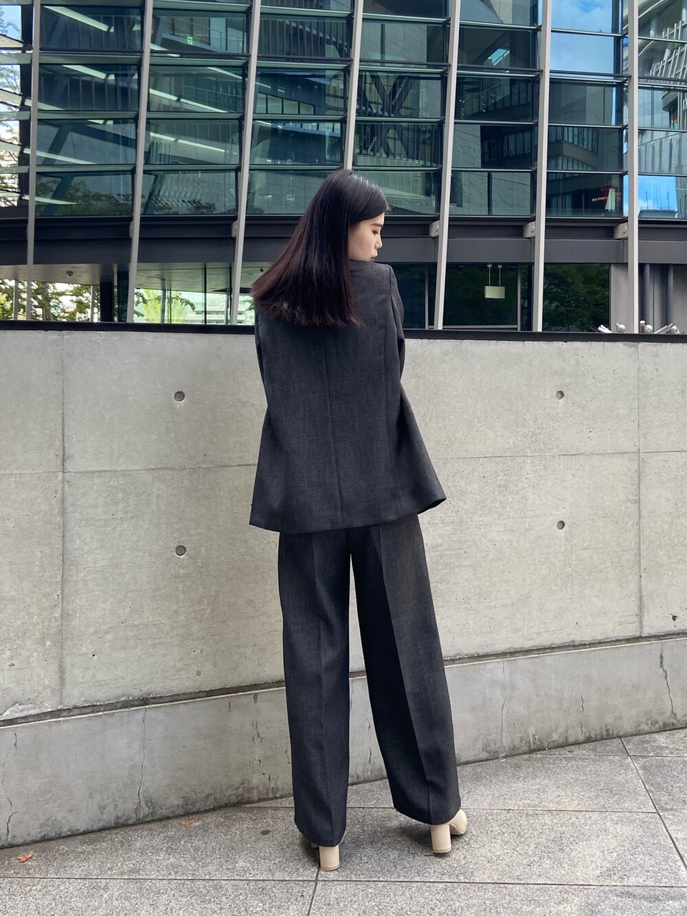 グレー系のテーラードジャケット、ブラック系のニット/セーター、グレー系のスラックスを着用したレディースの秋コーディネートの3枚目の写真