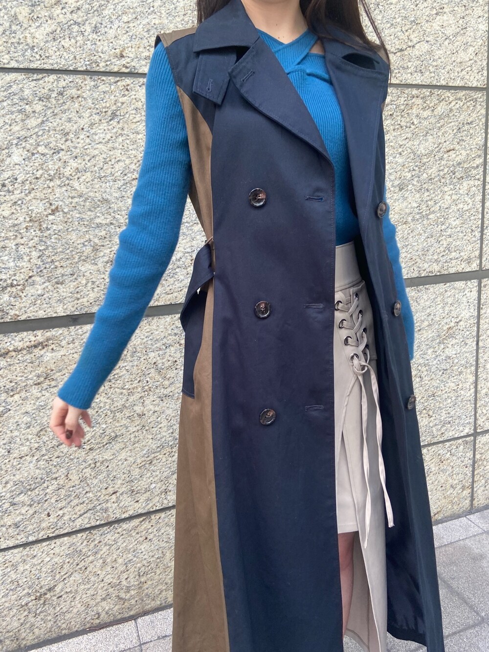 ブルー系のトレンチコート、ホワイト系のスカート、ブラック系のブーツを着用したレディースの秋コーディネートの5枚目の写真