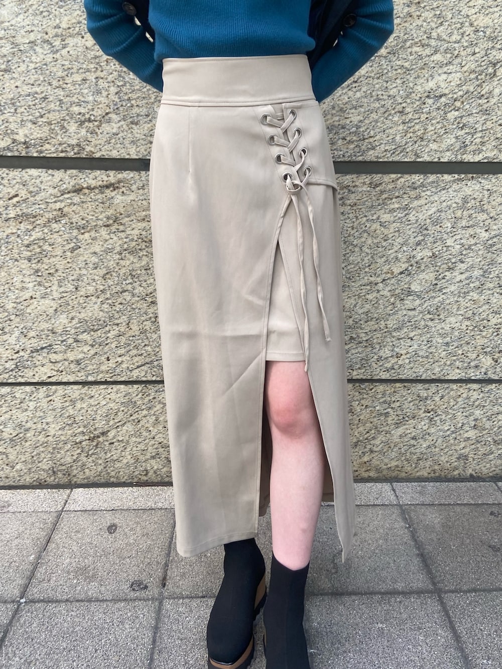 ブルー系のトレンチコート、ホワイト系のスカート、ブラック系のブーツを着用したレディースの秋コーディネートの7枚目の写真