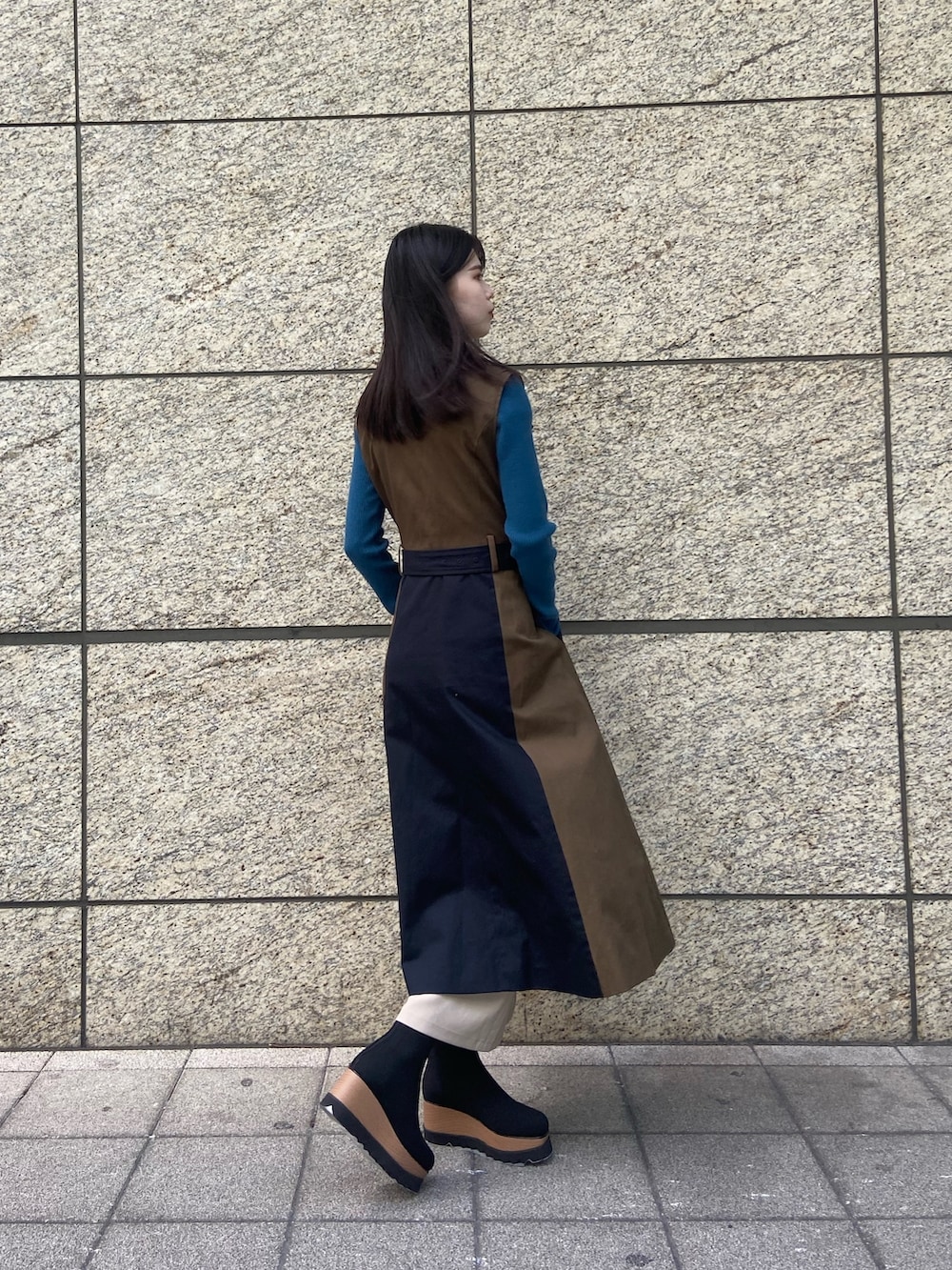 ブルー系のトレンチコート、ホワイト系のスカート、ブラック系のブーツを着用したレディースの秋コーディネートの3枚目の写真