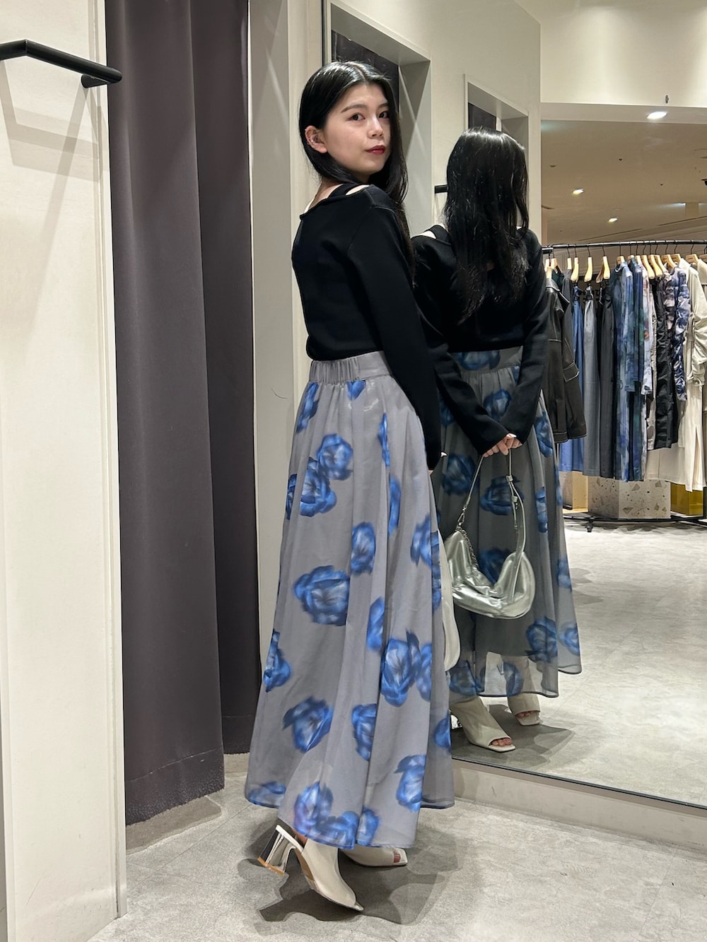 ブラック系のニット/セーター、グレー系のスカート、ホワイト系のブーツを着用したレディースの春コーディネートの2枚目の写真