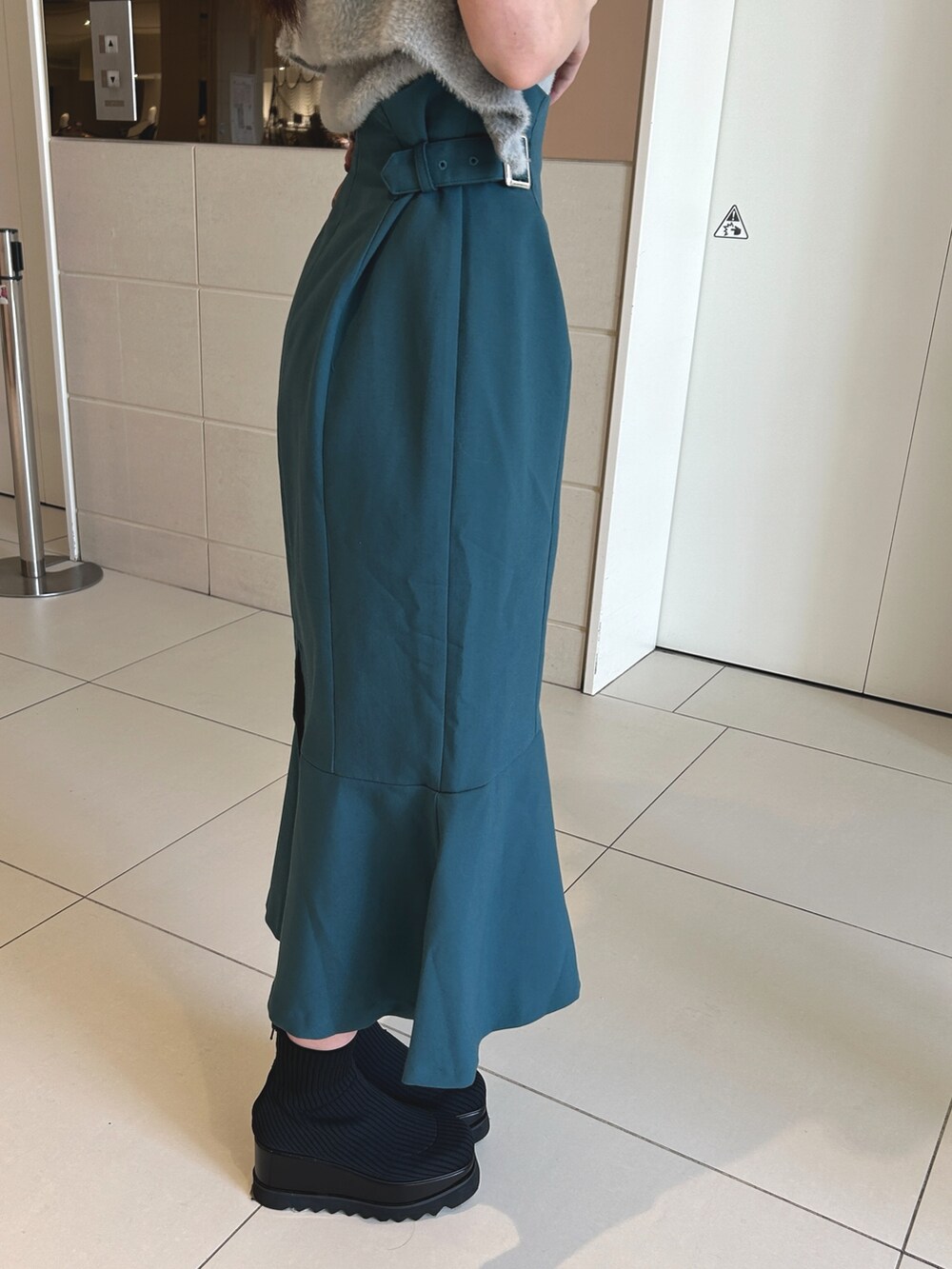 ブルー系のスカート、グレー系のニット/セーター、ブラック系のブーツを着用したレディースの秋コーディネートの6枚目の写真