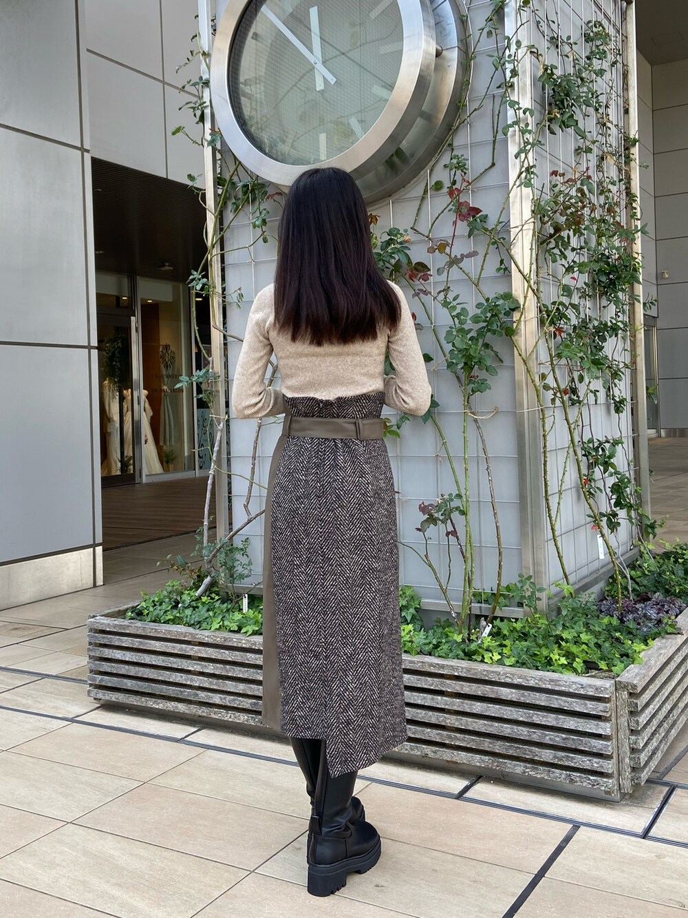 ブルー系のステンカラーコート、ベージュ系のニット/セーター、ブラウン系のスカートを着用したレディースの秋コーディネートの6枚目の写真