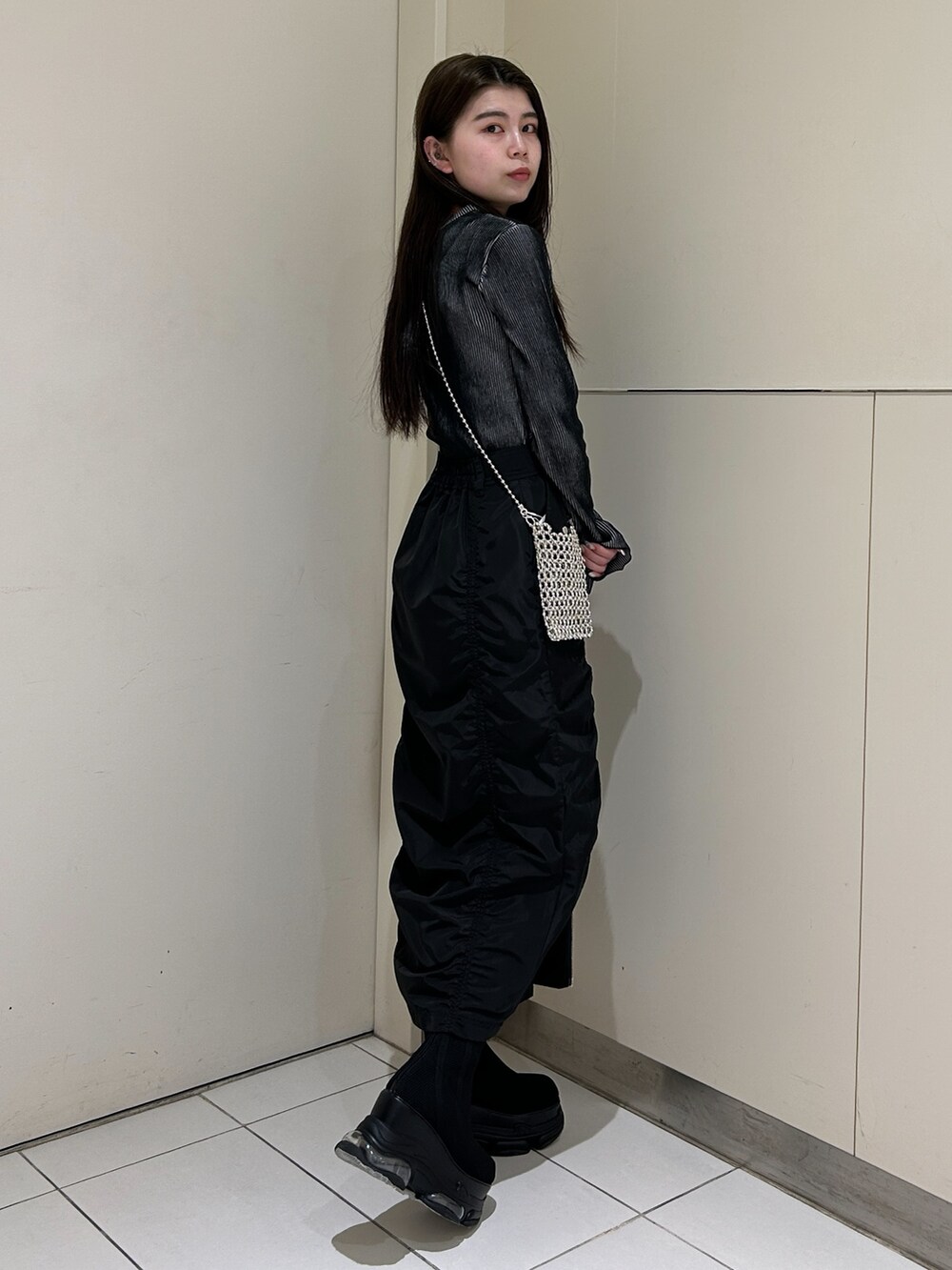 ブラック系のスカート、ブラック系のニット/セーター、ブラック系のブーツを着用したレディースの春コーディネートの2枚目の写真