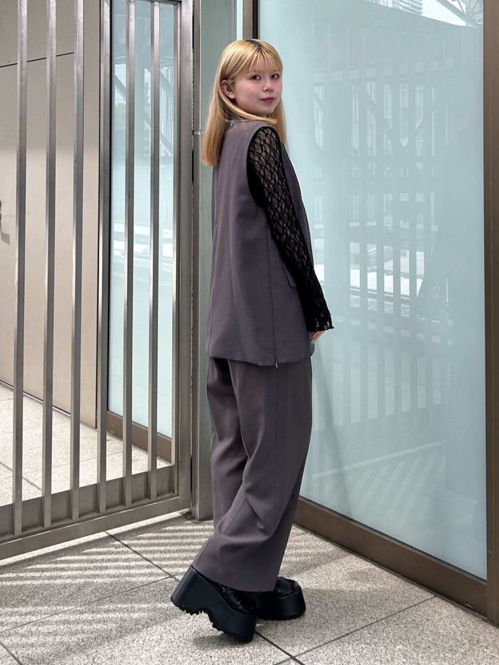 グレー系のベスト、グレー系のスラックス、ブラック系のTシャツ/カットソーを着用したレディースの春コーディネートの2枚目の写真