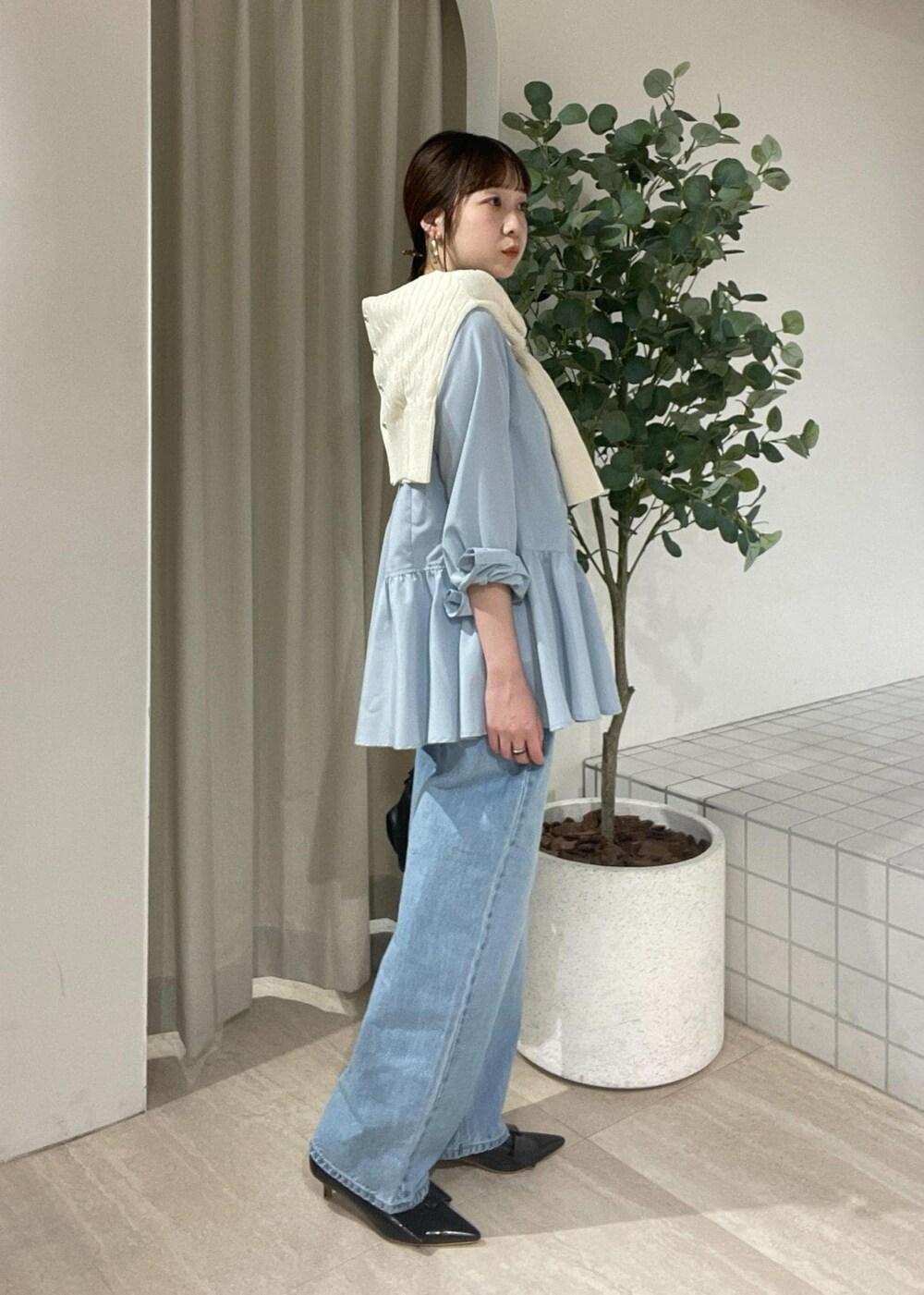 ブラック系のパンプス、ブルー系のシャツ/ブラウス、ホワイト系のカーディガン/ボレロを着用したレディースの冬コーディネートの2枚目の写真