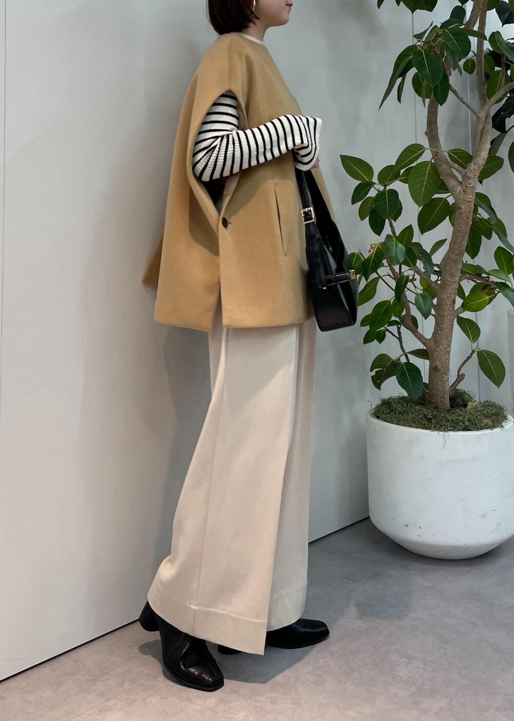 ブラック系のハンドバッグ、ベージュ系のポンチョ、ベージュ系のその他パンツを着用したレディースの秋コーディネートの5枚目の写真