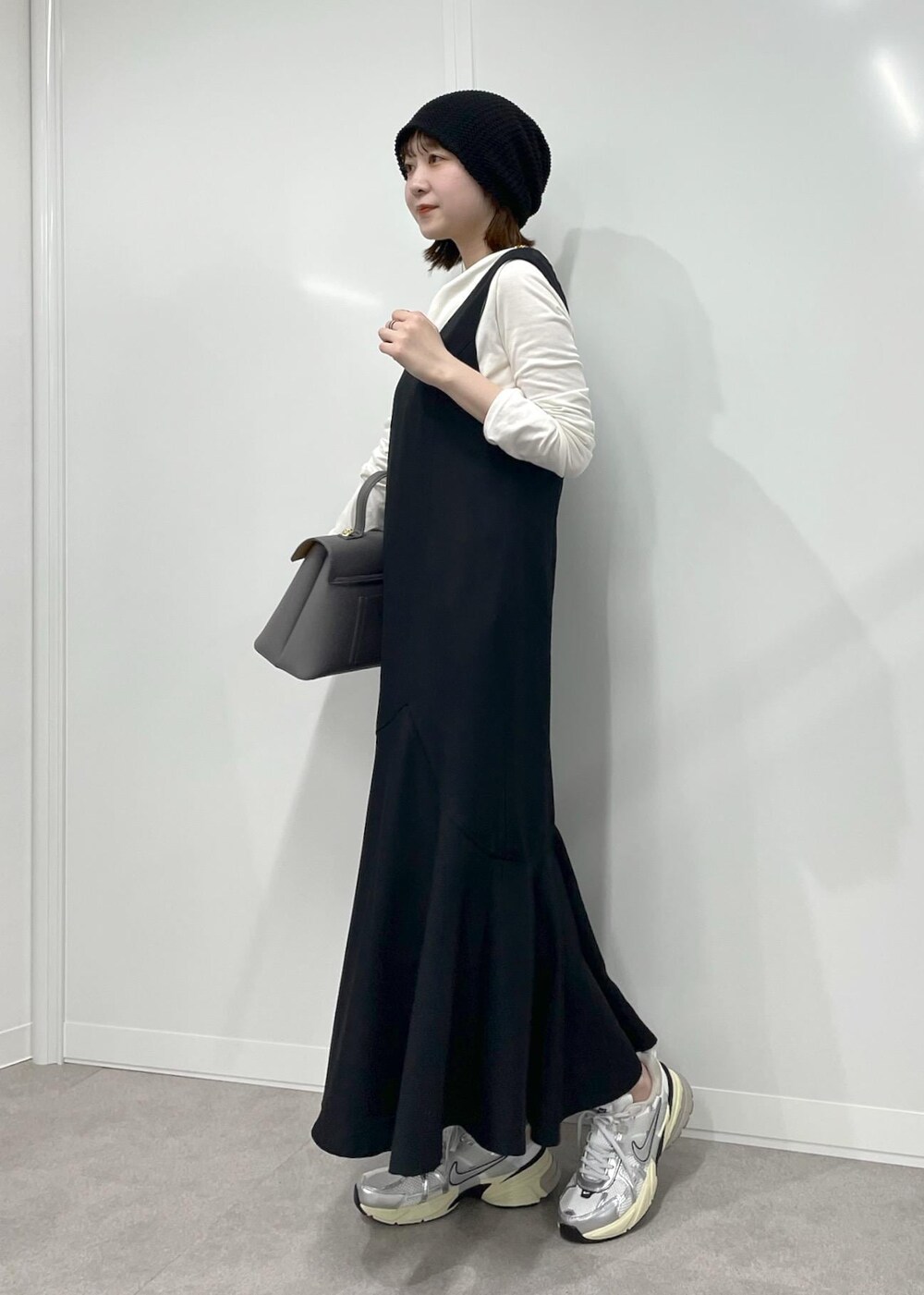 グレー系のハンドバッグ、ブラック系のワンピース、ホワイト系のTシャツ/カットソーを着用したレディースの冬コーディネートの6枚目の写真